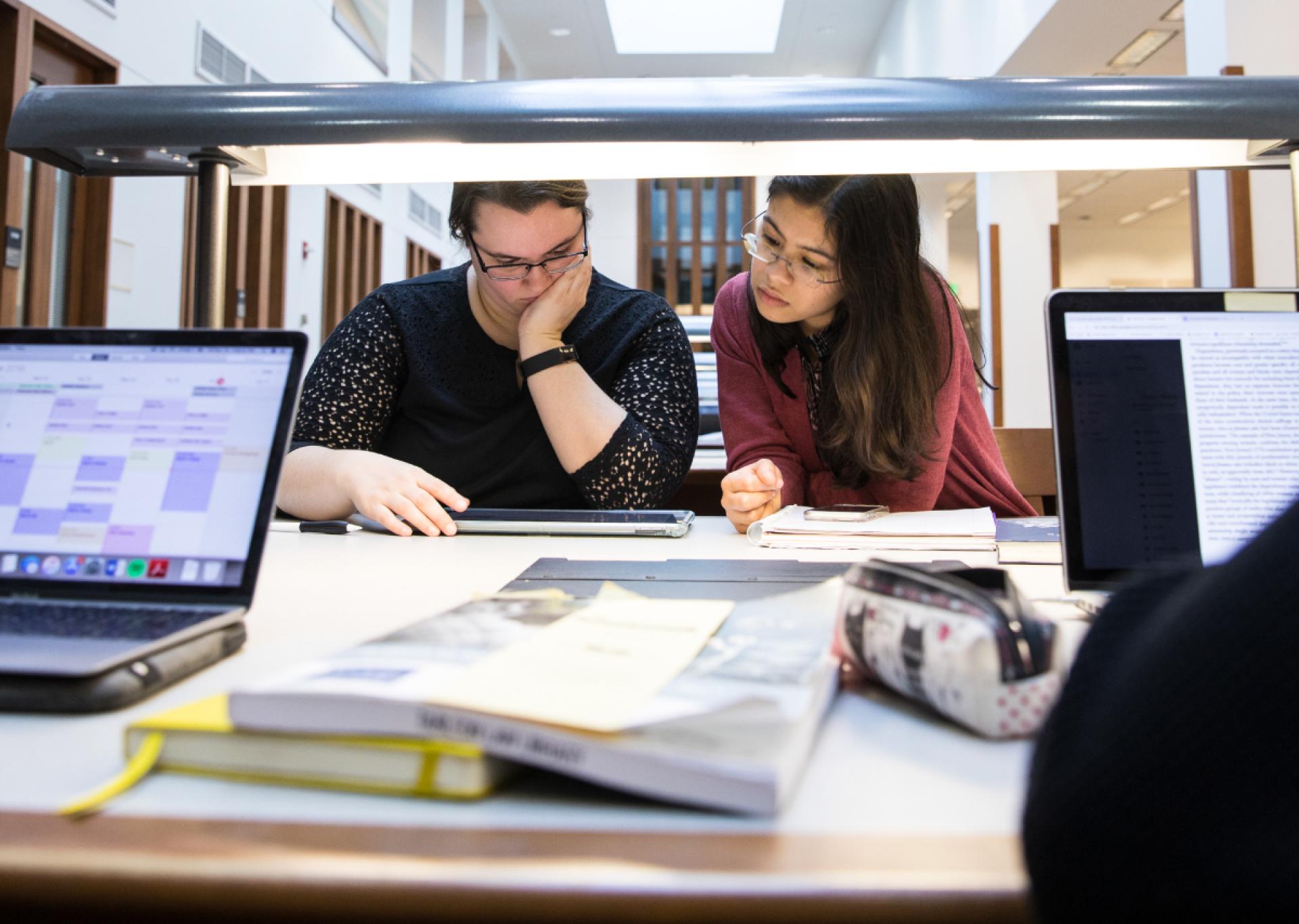 students in the library in front of books and a laptop